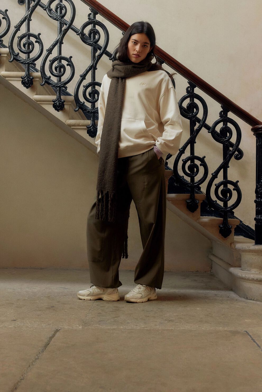 A person standing against a tan studio backdrop.